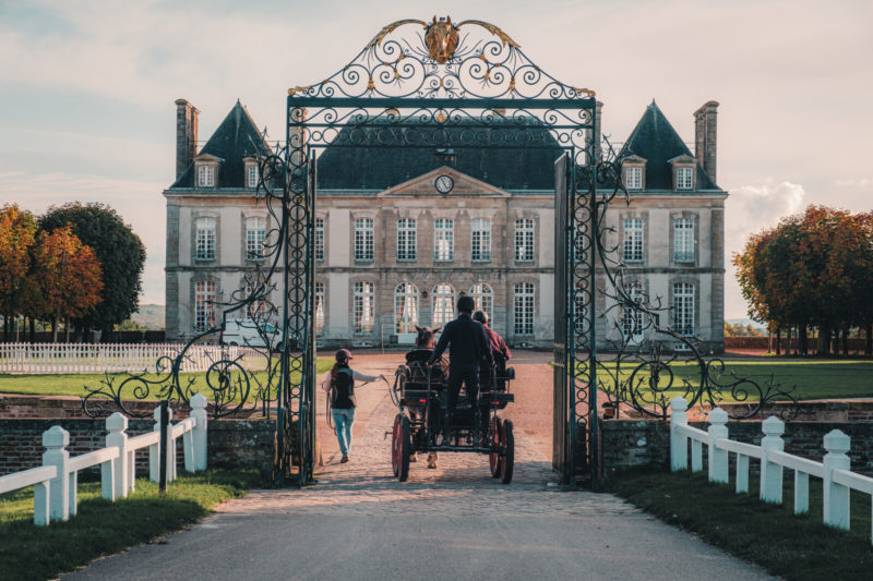 Calèche entrant dans le domaine du Haras du Pin, château en fond