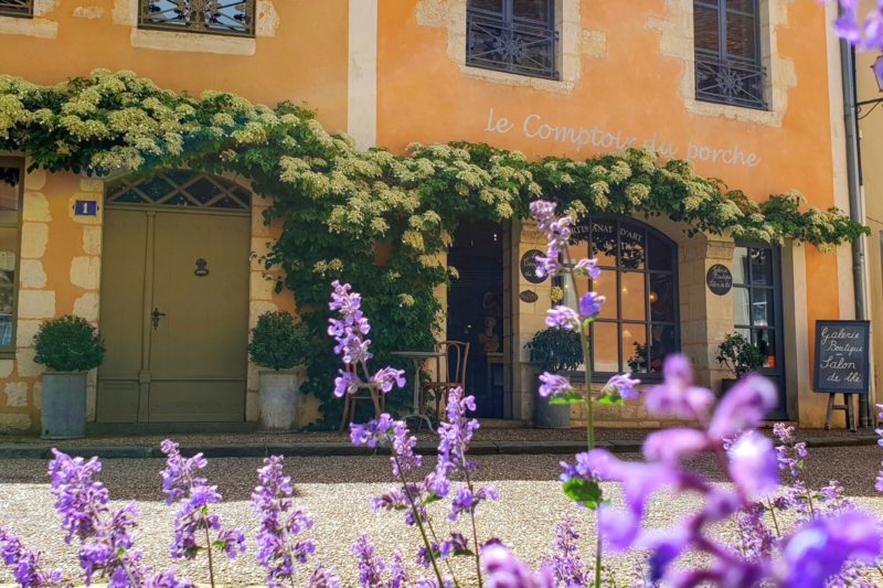 Vue sur façade jaune d'une maison de Bêlleme avec fleure de lavande en premier plan. Une vigne contourne les portes et fenêtres du premier étage.