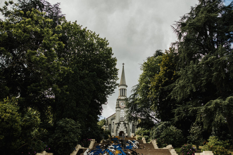 Escaliers avec peinture de street-art menant à l'église de Bagnoles-de-l'Orne et bordés d'arbres