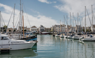 Port de Saint-Vaast-la-Hougue en Normandie, avec bateaux de pêche amarrés et maisons du littoral en arrière-plan.