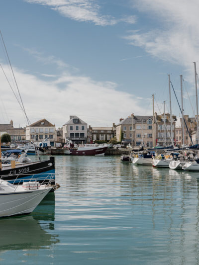 Port de Saint-Vaast-la-Hougue en Normandie, avec bateaux de pêche amarrés et maisons du littoral en arrière-plan.