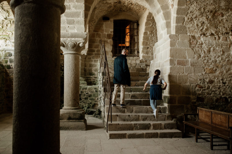 Découverte de l'abbaye du Mont-Saint-Michel. Vue sur les voutes et un escalier sur lequel se trouve un homme et une petite fille