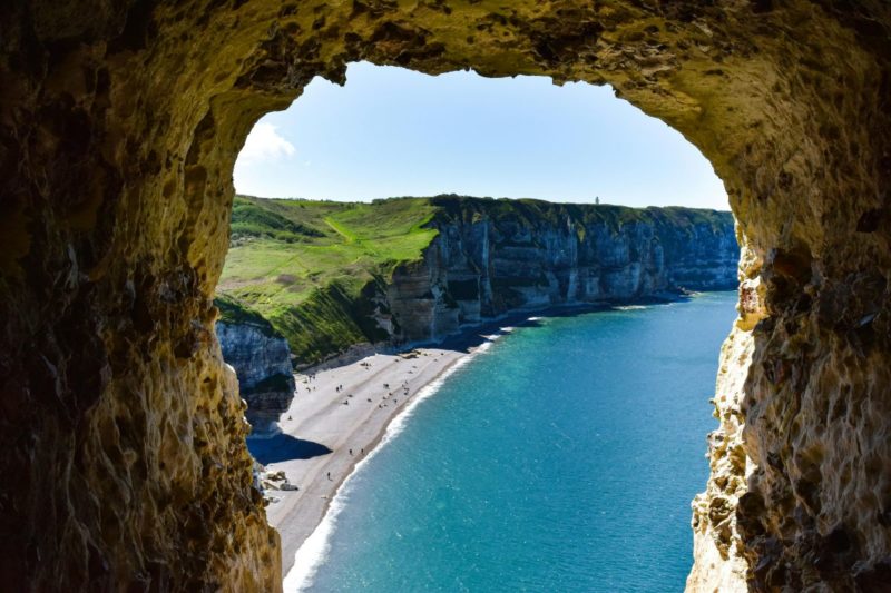 Vue sur la mer et les falaises d’Étretat encadrées par l’ouverture de la grotte d’Amour, en Normandie.